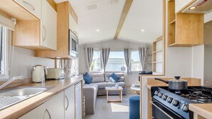 Eine kompakte Küchenzeile für Wohnmobile mit Herd, Spüle und einem Essbereich mit Sofa.