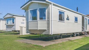 Ein Wohnmobil mit einer Veranda, einer Satellitenschüssel und einer kleinen angebauten Garage.