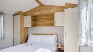 Ein Schlafzimmer mit Bett, Nachttisch, Kleiderschrank und einem Fenster mit Vorhängen.