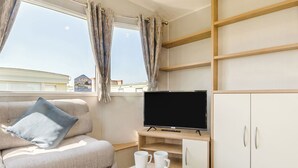Ein modernes Hotelzimmer mit Sofa, Fernseher und Frühstücksangebot.