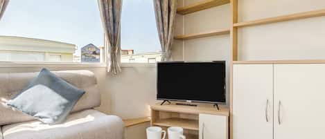 Habitación de hotel moderna con sofá, televisión y mesa para el desayuno.