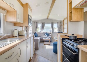 Cocina compacta para autocaravana, con estufa, fregadero y zona de comedor con sofá.