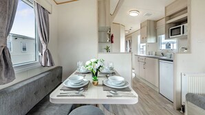 Een moderne woonwagenkeuken met een eethoek, ingebouwde apparatuur en uitzicht op het buitenland.