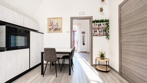 A modern kitchen with a dining area, a wooden door, and a hallway leading to another room.