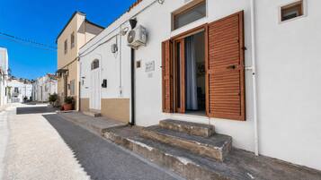 Un vicolo stretto con edifici bianchi, una porta di legno e gradini che conducono a un ingresso.