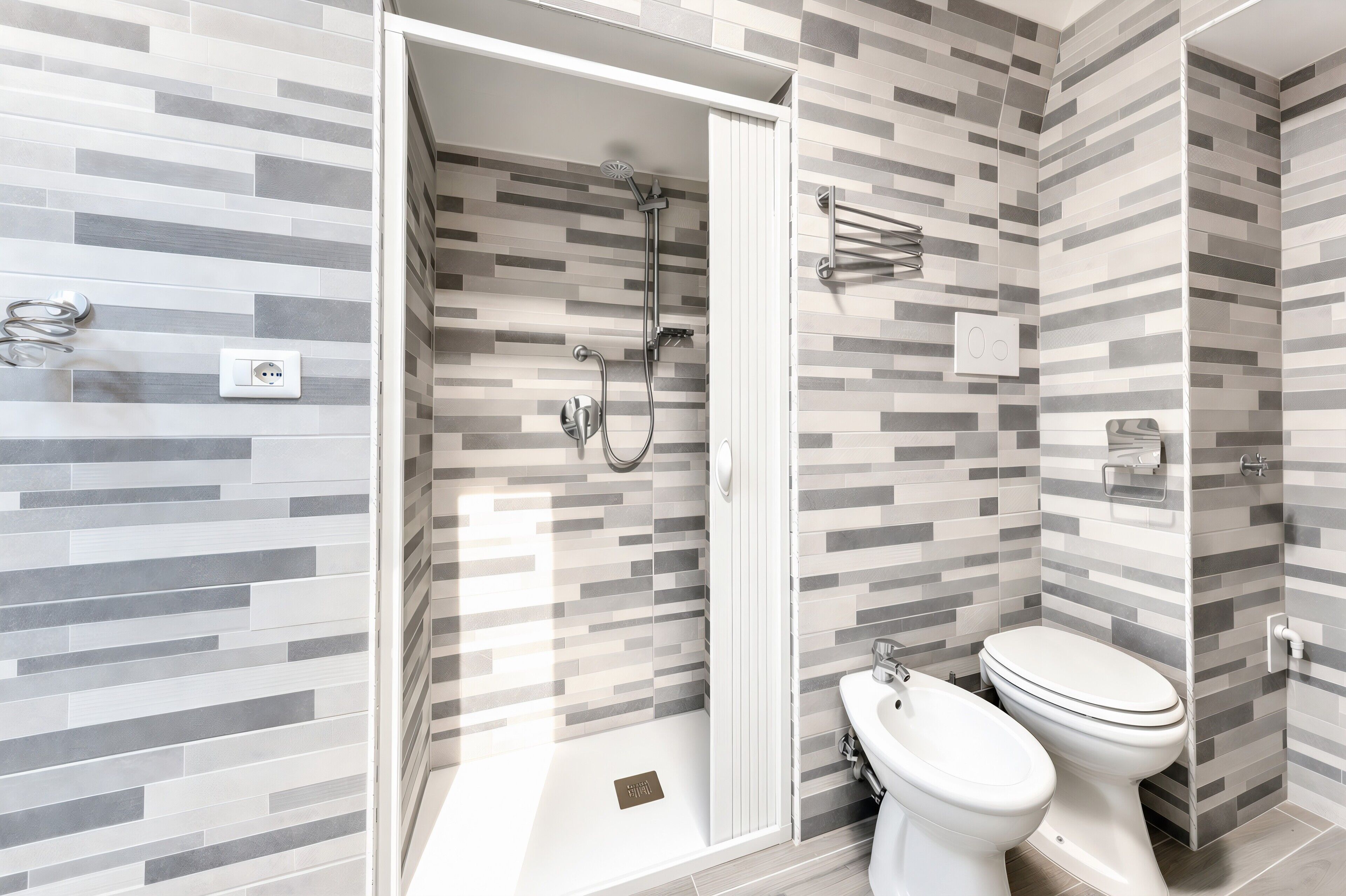 A modern bathroom with a shower, toilet, and bidet.