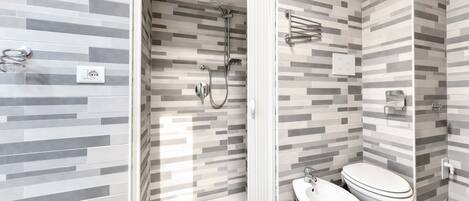 A modern bathroom with a shower, toilet, and bidet.