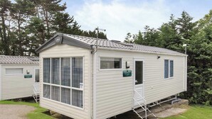 Uma casa móvel com uma janela grande, uma porta e um pequeno alpendre.