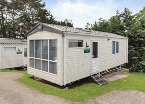 Une maison mobile dotée d’une grande fenêtre, d’une porte et d’un petit espace porche.