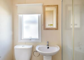 Une salle de bain équipée de toilettes, d’un lavabo, d’une fenêtre et d’un miroir.