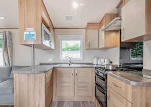 Une cuisine compacte avec des meubles en bois, une cuisinière intégrée et une fenêtre qui laisse entrer la lumière naturelle.
