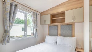 Ein Schlafzimmer mit Bett, Vorhängen, einem Fenster und eingebauten Holzkabinetten.