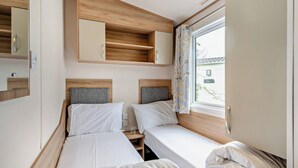 Ein gemütliches Schlafzimmer mit zwei Betten, einem Holzkopfstück, einer kleinen Ablagefläche und einem Fenster mit Blick.