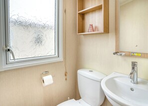 A bathroom with a toilet, sink, and a window with frosted glass.