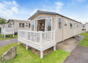 A mobile home with a porch, a small deck, and a window.