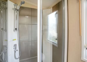 A modern bathroom with a glass shower enclosure, a toilet, and a window.