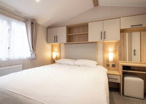 Un dormitorio con cama, mesitas de noche, escritorio y armarios empotrados.