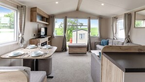 Interior de una caravana con comedor, kitchenette y zona de estar.