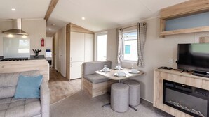 Interior moderno de autocaravana con kitchenette, comedor y zona de estar.