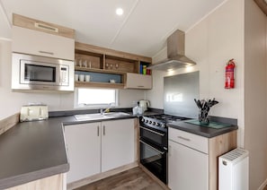 Eine moderne Küche mit Mikrowelle, Toaster, Spüle, Herd und Holzschränken.