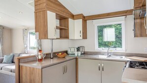 Une cuisine compacte avec des meubles en bois, une cuisinière intégrée et une fenêtre donnant sur un espace verdoyant.
