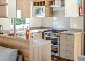 Une cuisine moderne équipée d’une cuisinière à gaz, d’un four, d’un four à micro-ondes et d’appareils électroménagers en acier inoxydable.