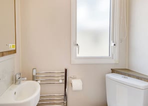 A bathroom with a toilet, a bidet, a towel rack, and a window. - Silver Premium 3 Bedroom Caravan, Sleeps 8 (Walton-on-the-Naze)
