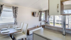 Una cocina moderna con comedor, televisor en la pared y vistas al exterior.