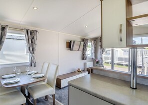 Una cocina moderna con comedor, televisor en la pared y vistas al exterior.
