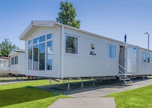 A mobile home with a large window, a door, and a small attached structure. - Silver Premium 3 Bedroom Caravan, Sleeps 8 (Walton-on-the-Naze)