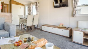 Ein modernes Wohnzimmer mit einer Couch, einem Esstisch und einem Fernseher.