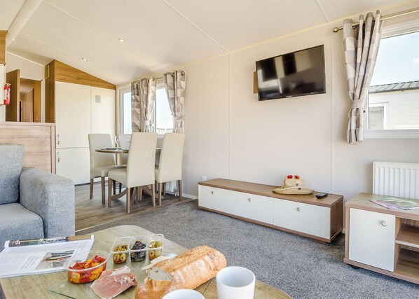 Una sala de estar moderna con sofá, mesa de comedor y televisor.