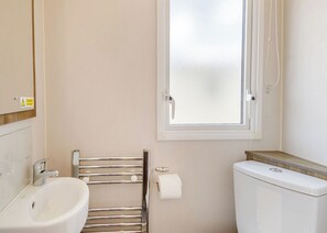 Un baño con inodoro, bidé, toallero y ventana.