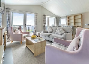 A spacious living room with a sofa, chairs, a coffee table, and a bookshelf.