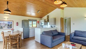Eine moderne Küche mit Kühlschrank, Mikrowelle und Spüle. Es gibt einen Essbereich mit Tisch und Stühlen sowie ein Wohnzimmer mit Sofa und Couchtisch.
