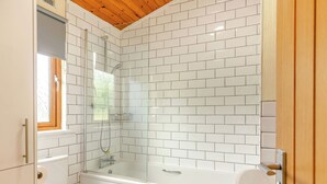 A bathroom with white tiled walls, a bathtub, a toilet, and a shower enclosure. - Deluxe Lodge with ensuite & decking (Walton-on-the-Naze)