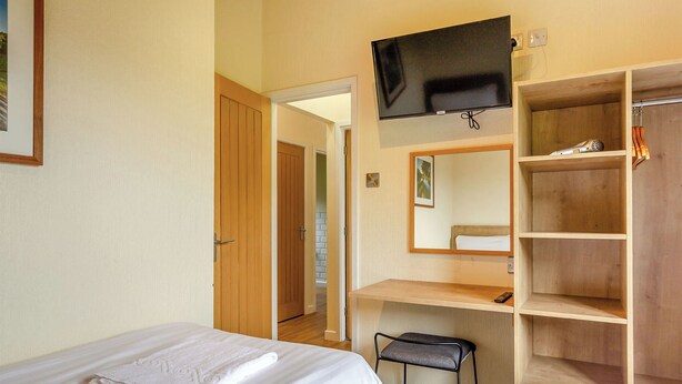 Ein Hotelzimmer mit zwei Betten, einem Fernseher, einem Spiegel und einem Holzschrank.