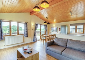 Ein geräumiger Wohnbereich mit Sofa, Esstisch, Stühlen, Holzboden und einer Küchenzeile.