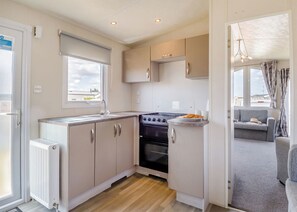 Uma cozinha compacta com fogão, pia e armários, um radiador e vista para o exterior.