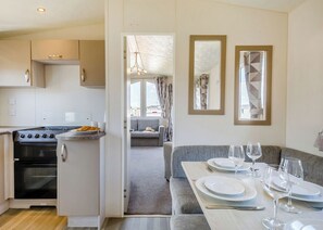 Cocina moderna con estufa, horno y comedor con una mesa dispuesta para dos personas.
