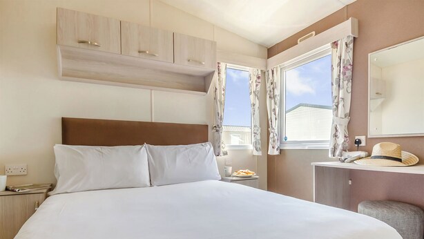 A hotel room with a large bed, a desk with a chair, a mirror, and a window with curtains. - Gold Accessible with parking P (Walton-on-the-Naze)