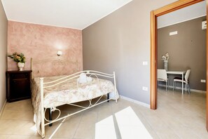 A bedroom with a bed, bedside table, lamp, and a small potted plant. - Casa Carrubo - Villa Mapa with Sea View, Wi-Fi & Air Conditioning (Vieste)