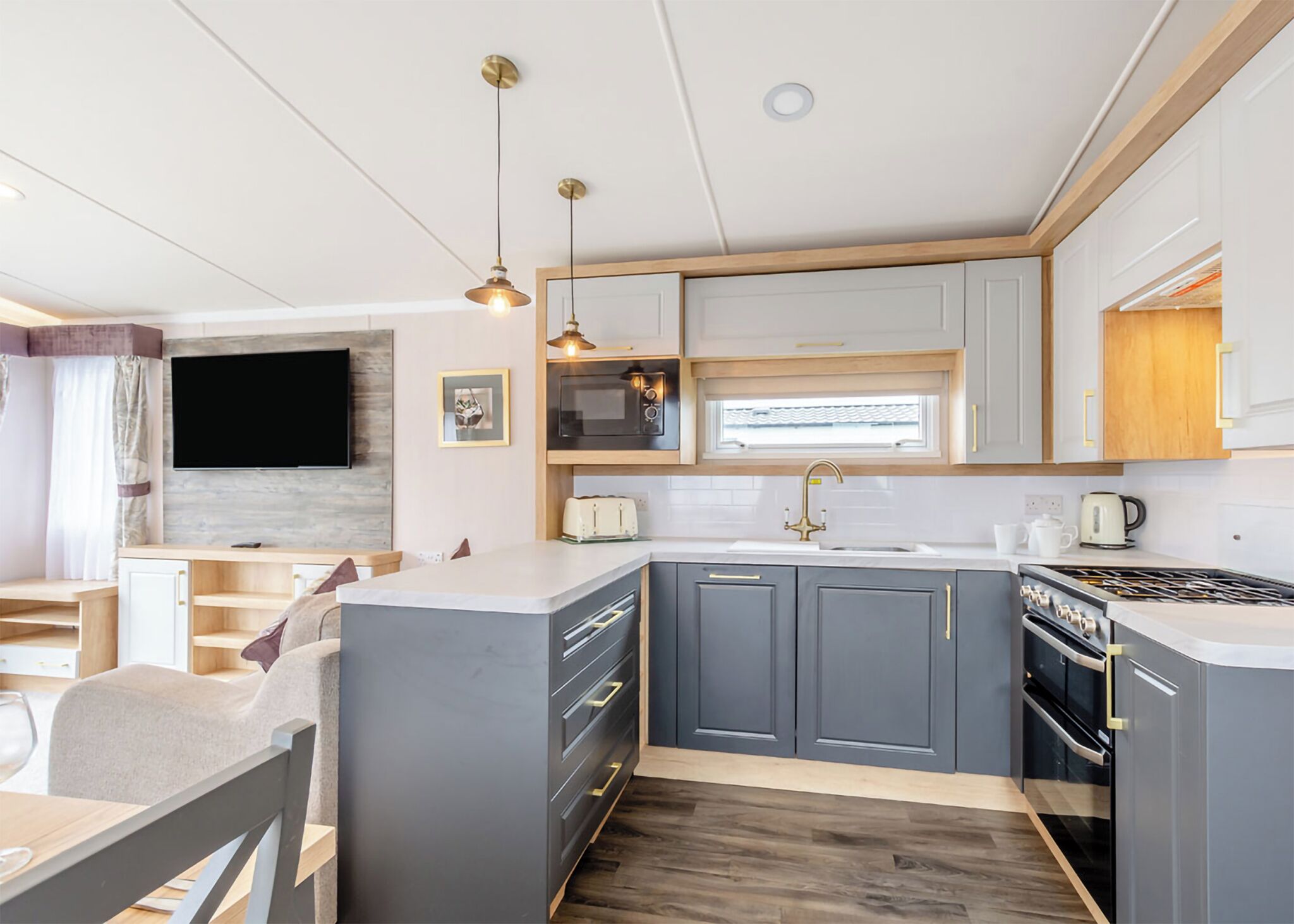 A modern kitchen with grey cabinets, a central island, a built-in oven, and pendant lighting.