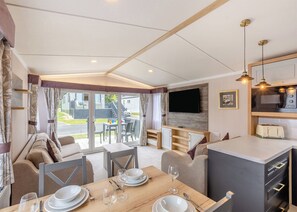 L’intérieur d’une caravane comprend un coin repas, une cuisine et un téléviseur fixé au mur.