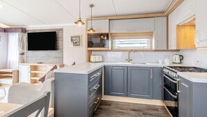 Een moderne keuken met grijze kastjes, een centraal eiland, een inbouwoven en hanglampen.