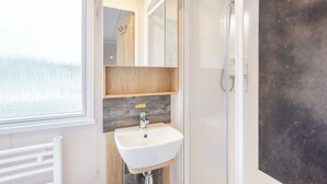 Een moderne badkamer met een wit wastafel, houten wastafelmeubel en een grote spiegel.