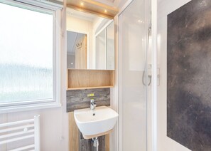 A modern bathroom with a white sink, wooden vanity, and a large mirror. - Gold Premium Caravan, parking, ensuite, deck, SV 6 (Ryde, Nr Bembridge)