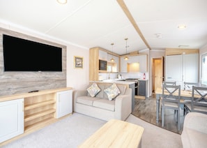 A compact living space with a TV, sofa, dining table, kitchen area, and a small island. - Gold Premium Caravan parking, ensuite, deck SV 6 P (Ryde, Nr Bembridge)
