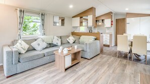 A modern living area with a sofa, coffee table, and dining table. - Gold Premium Caravan, parking, ensuite, deck & SV (Ryde, Nr Bembridge)
