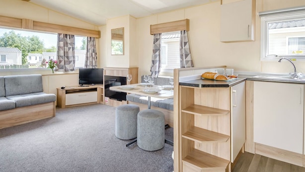 A compact RV interior with a kitchenette, a seating area, and a TV. - Gold 2 Bedroom Caravan, Sleeps 6 (Ryde, Nr Bembridge)